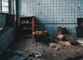 Old house with damaged furniture near weathered wall